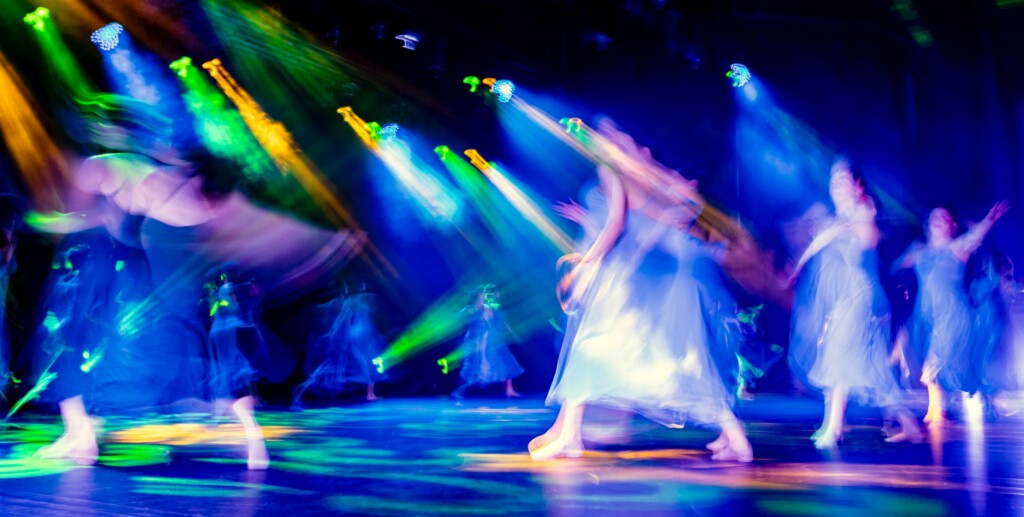 Blurry dancers dancing on a stage with colorful spotlights