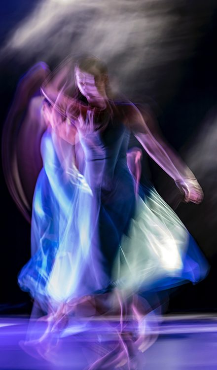 Dancer in a dress, unfocused, dark background.